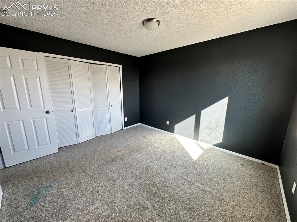 Image 9 of 16: Unfurnished bedroom featuring carpet, a textured ceiling, and a closet
