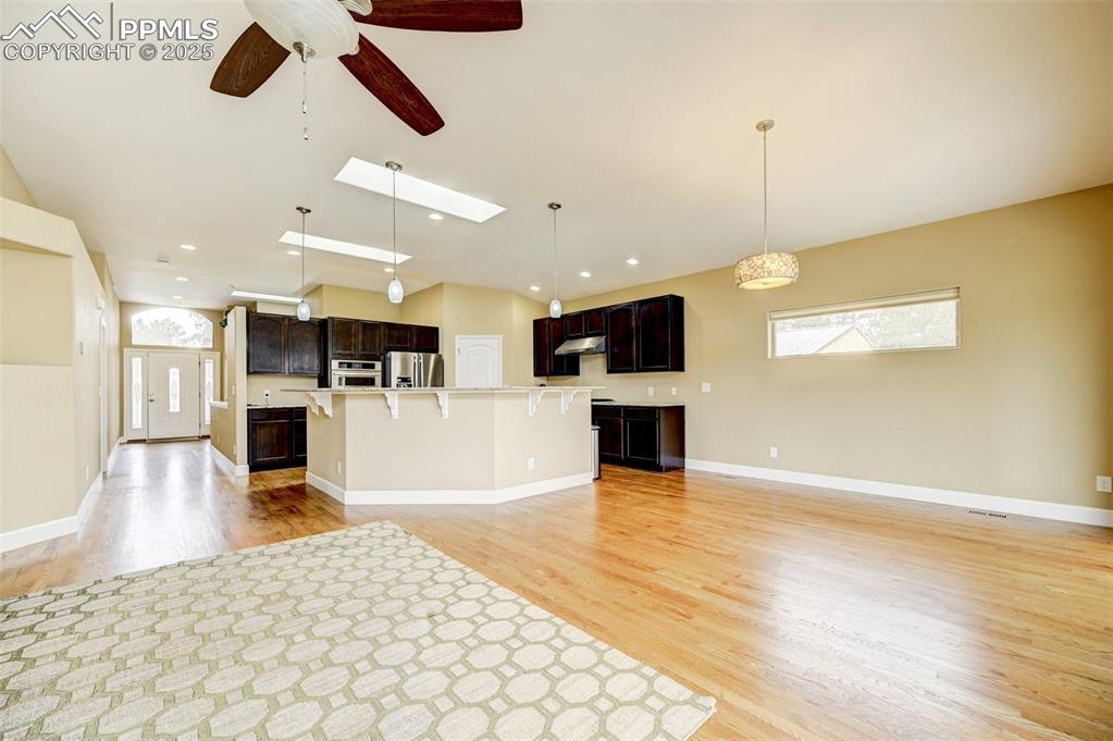 Image 11 of 30: Kitchen with ceiling fan, under cabinet range hood, light wood-style floors