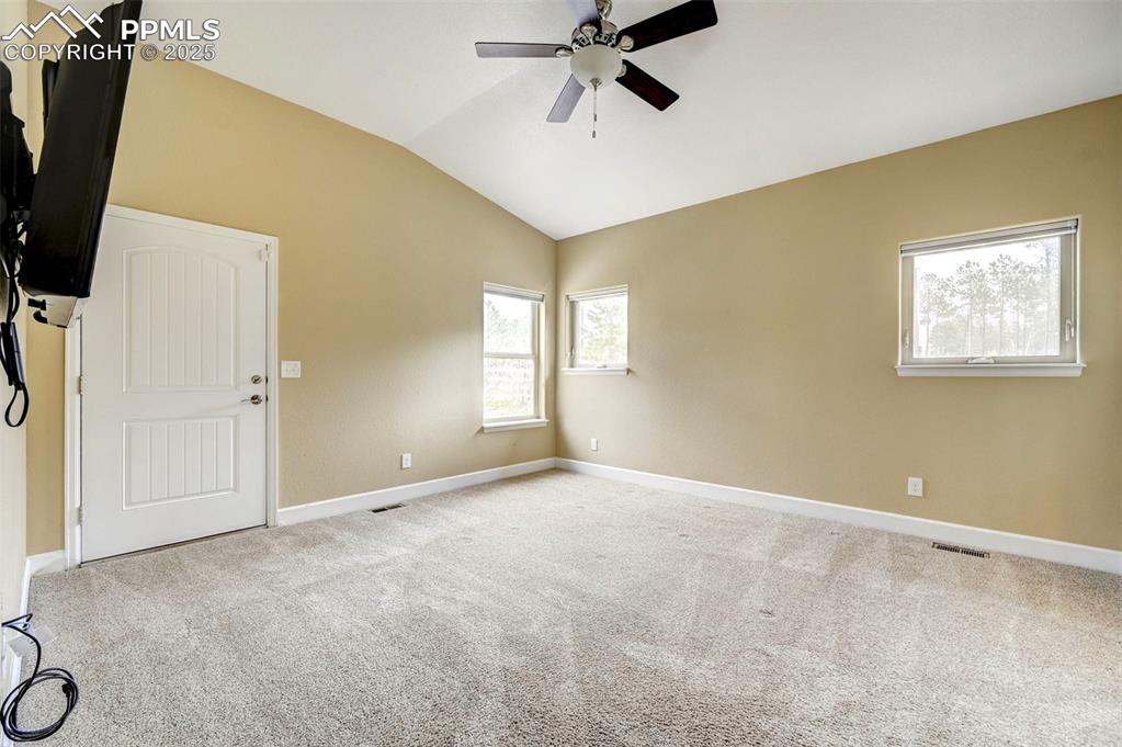 Image 14 of 30: Empty room featuring ceiling fan, carpet, baseboards, vaulted ceiling, and