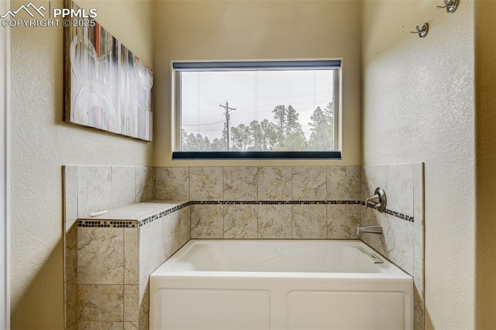 Image 15 of 30: Full bath featuring a textured wall and a bath