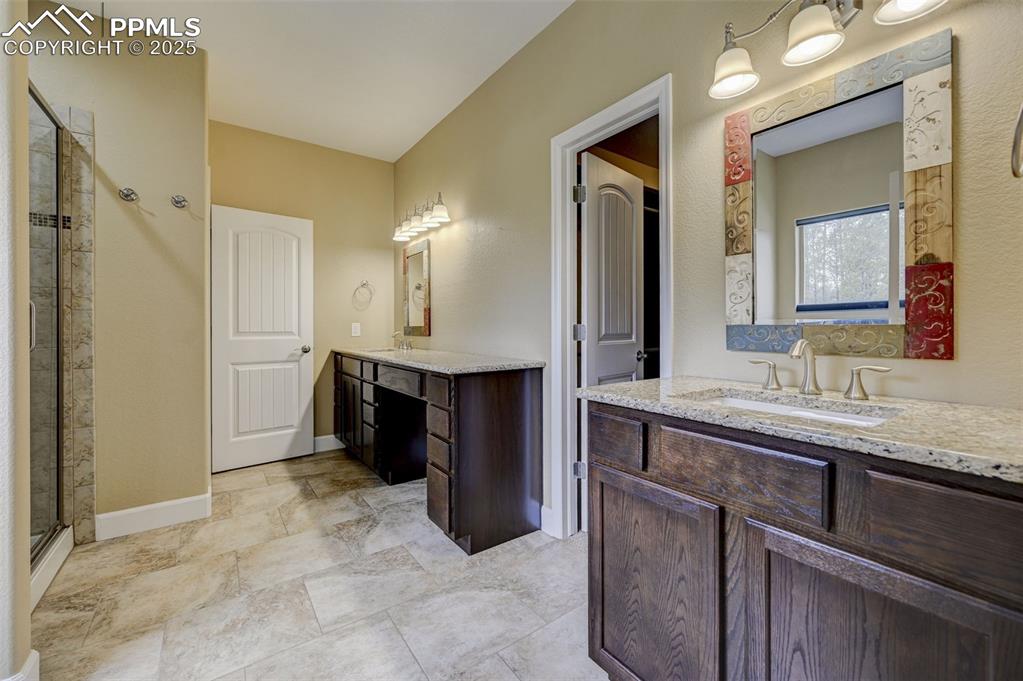 Image 17 of 30: Bathroom with baseboards, a sink, two vanities, and a shower stall