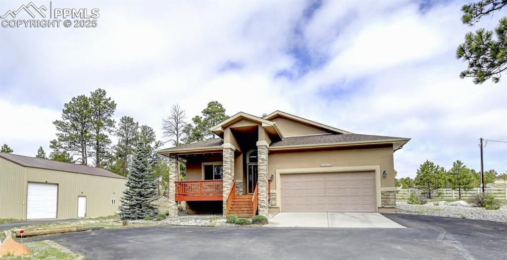 Image 2 of 30: Mid-century inspired home featuring covered porch, a garage, aphalt drivewa