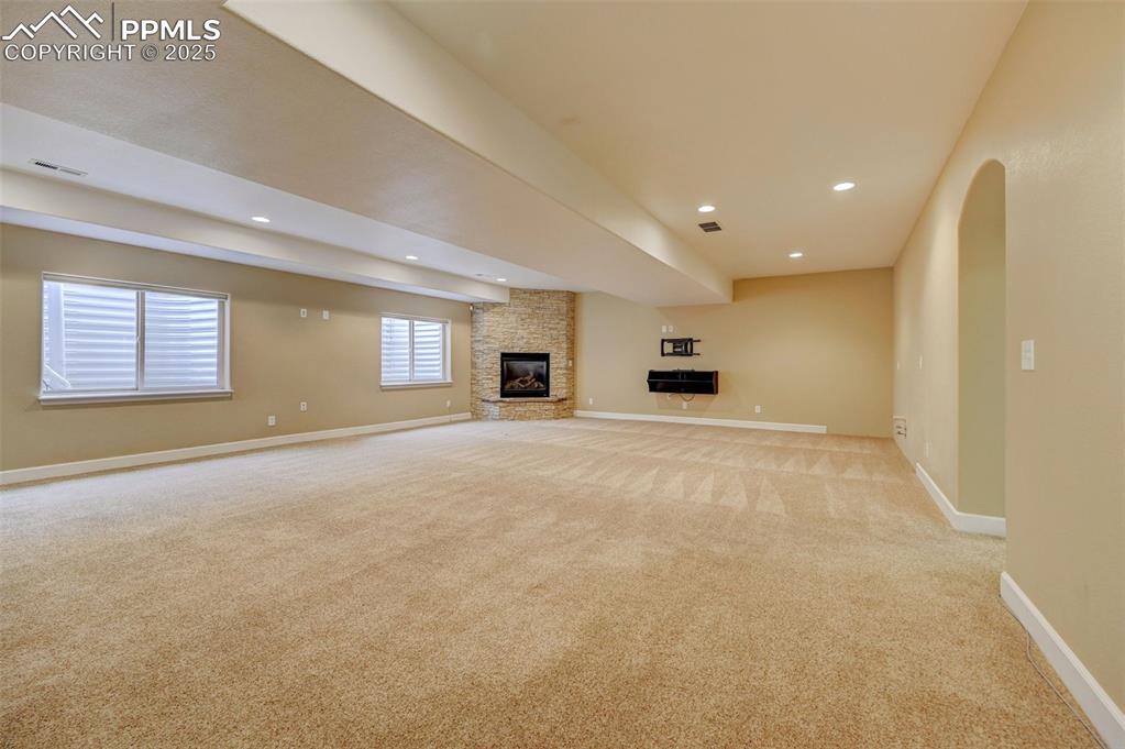 Image 21 of 30: Unfurnished living room featuring a stone fireplace, recessed lighting, bas