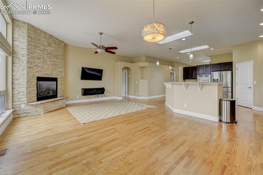 Image 7 of 30: Unfurnished living room with a stone fireplace, light wood-style flooring,