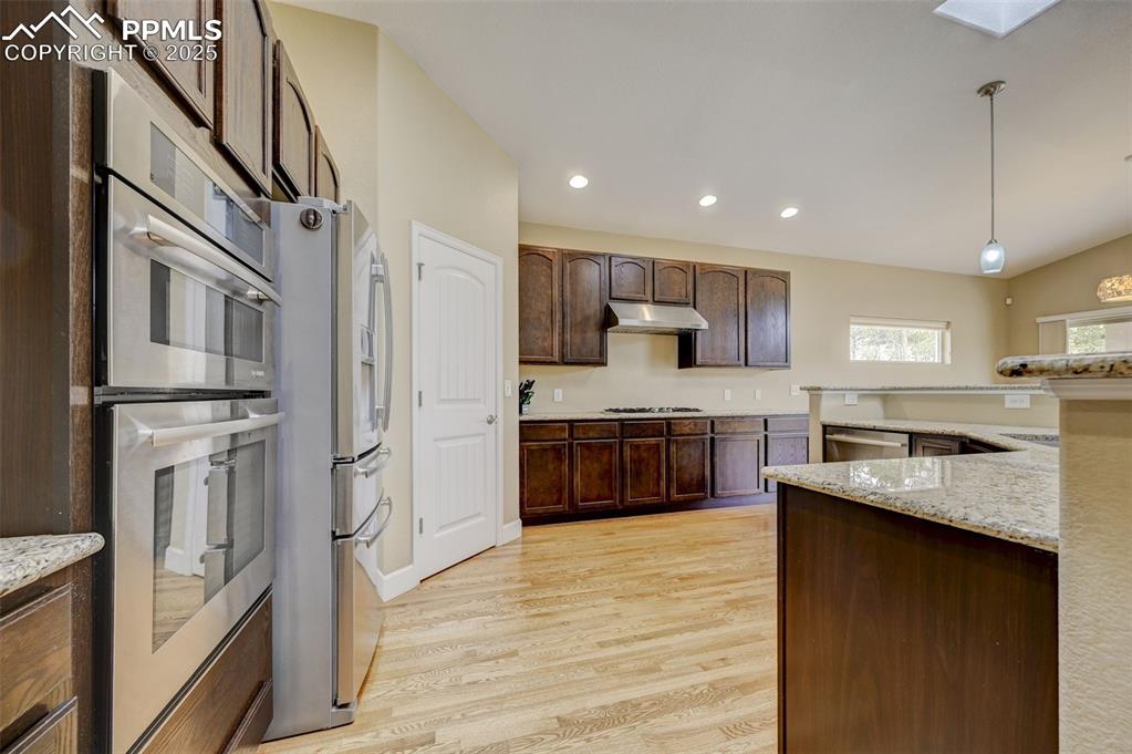 Image 8 of 30: Kitchen with pendant lighting, appliances with stainless steel finishes, li
