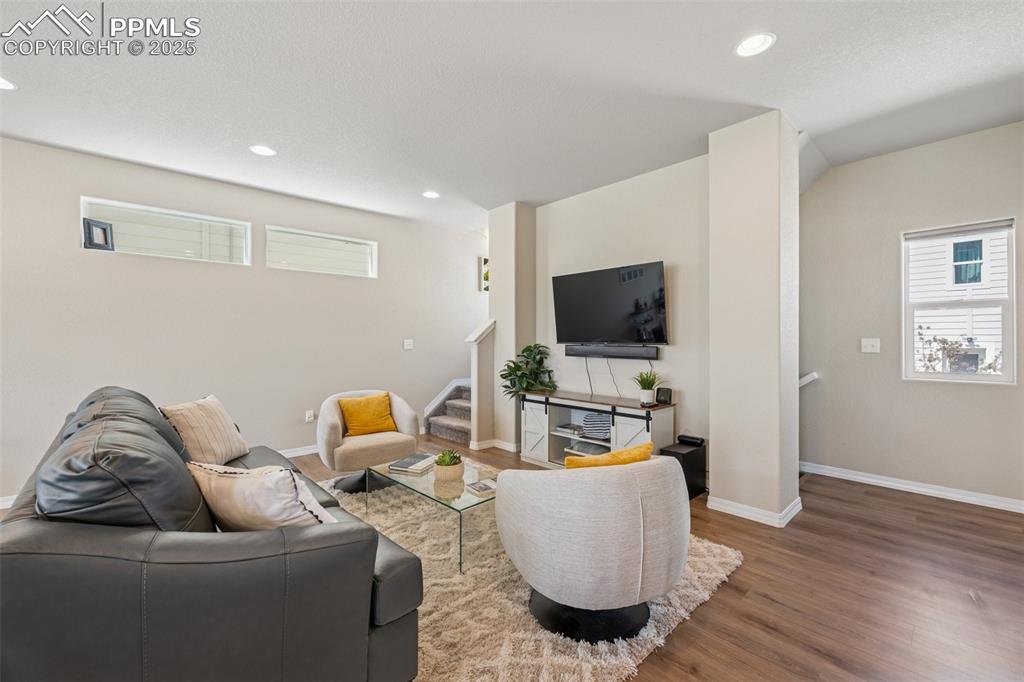 Image 14 of 29: Living room featuring stairs, wood finished floors, healthy amount of natur
