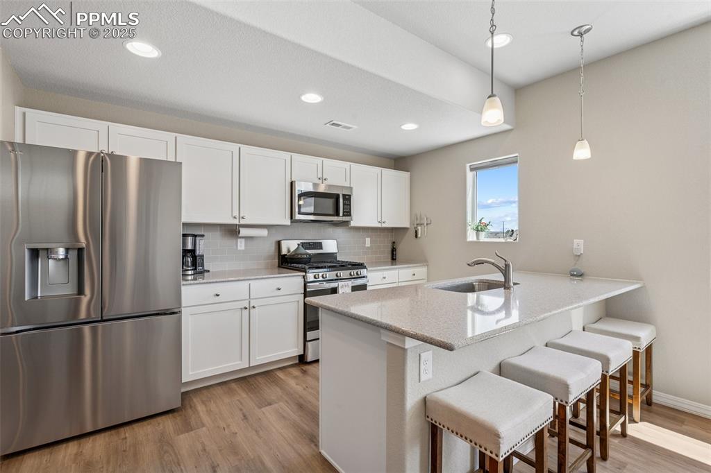 Image 18 of 29: Kitchen with appliances with stainless steel finishes, a sink, light wood-s
