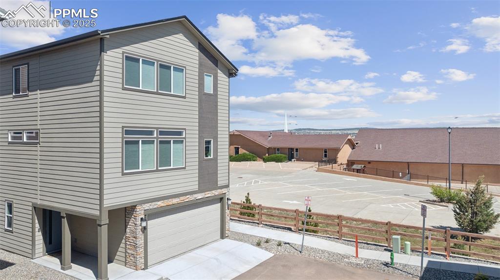 Image 2 of 29: View of property exterior with stone siding, an attached garage, and concre