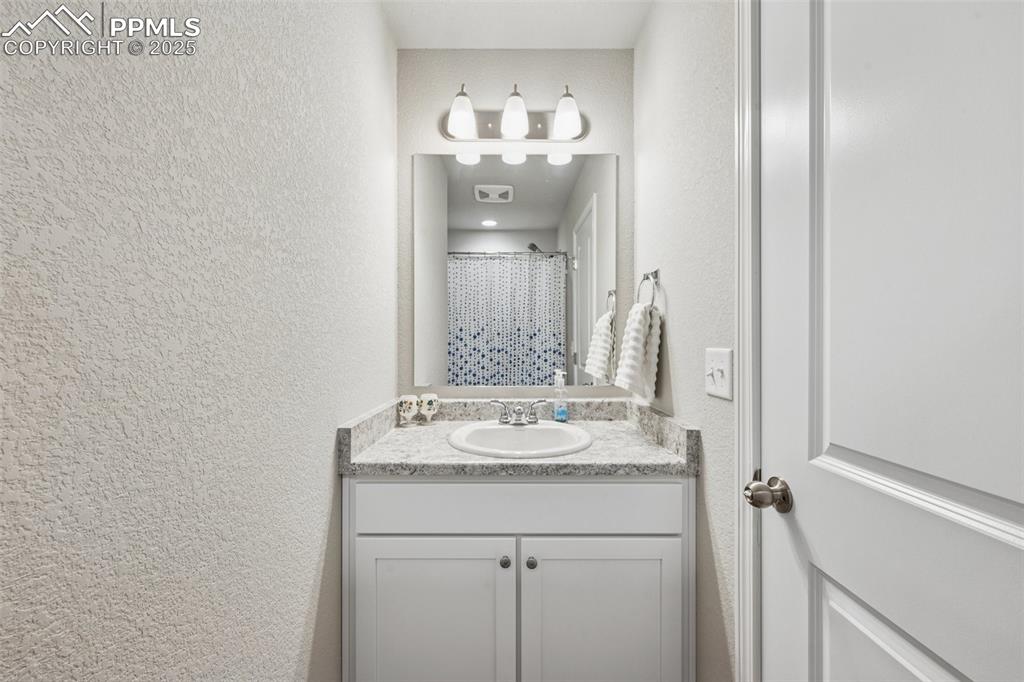 Image 23 of 29: Bathroom with a textured wall and vanity