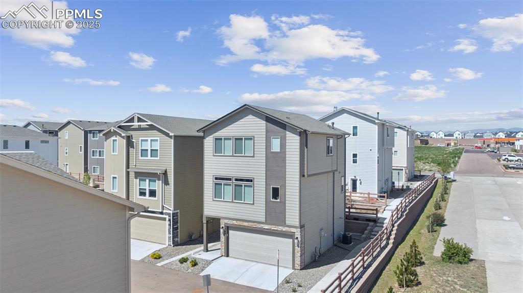 Image 4 of 29: Rear view of house featuring a residential view, an attached garage, and dr