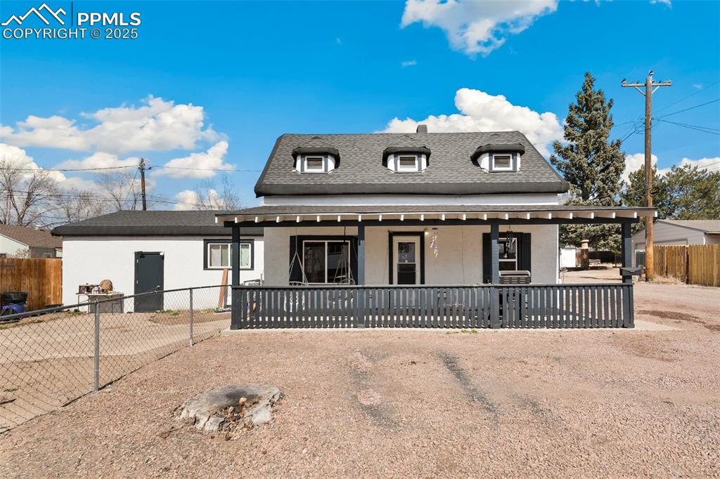 Image 33 of 49: View of front facade with a shingled roof, fence, and stucco siding