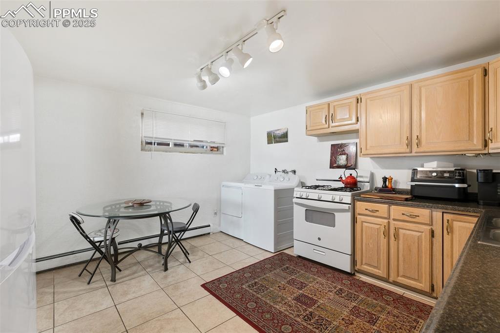 Image 8 of 49: Kitchen featuring gas range gas stove, dark countertops, separate washer an