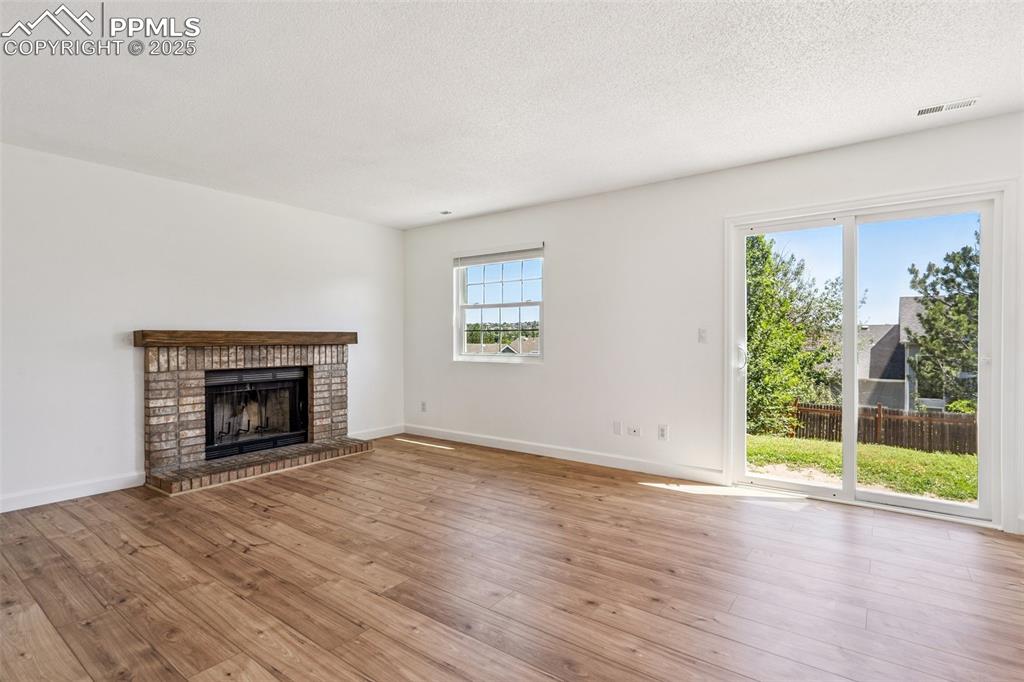Image 10 of 22: Unfurnished living room featuring hardwood / wood-style flooring, a firepla