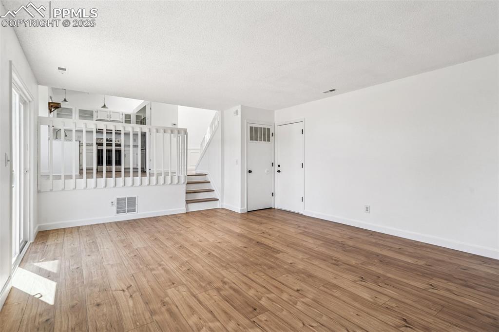 Image 11 of 22: Empty room with hardwood / wood-style flooring, stairs, and a textured ceil