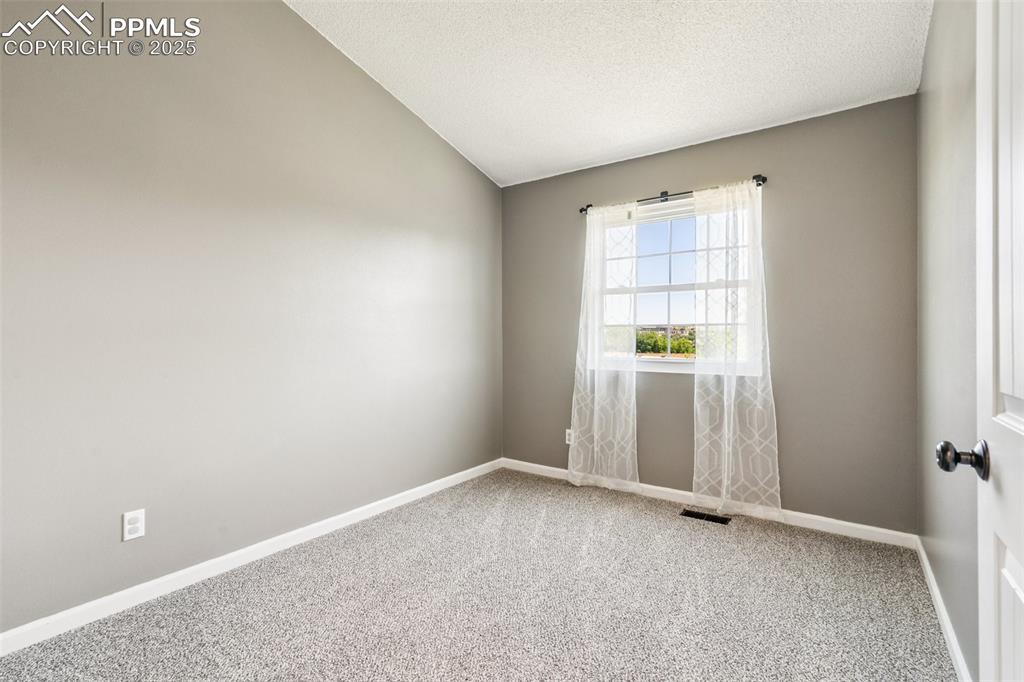 Image 13 of 22: Carpeted spare room with a textured ceiling and lofted ceiling