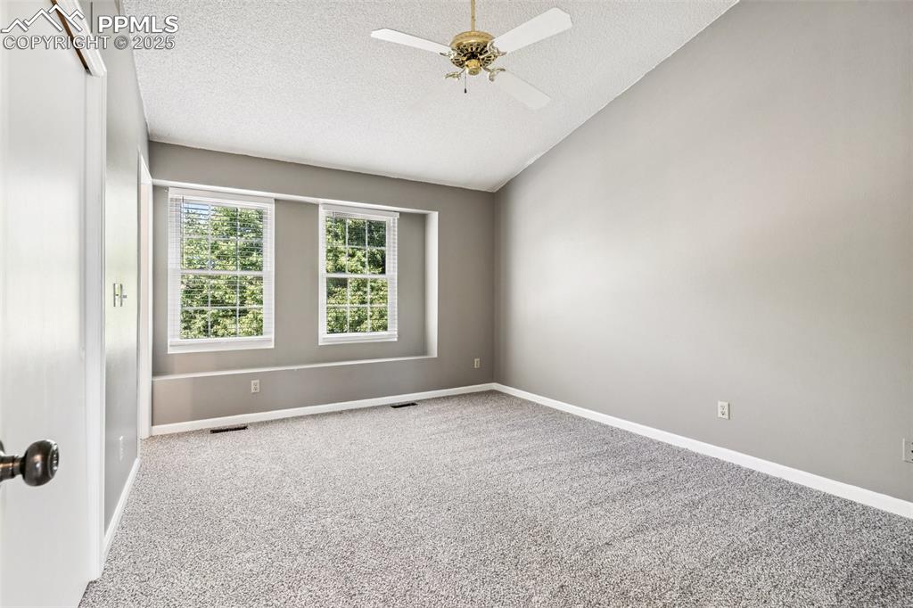 Image 15 of 22: Carpeted empty room with a textured ceiling, vaulted ceiling, and ceiling f
