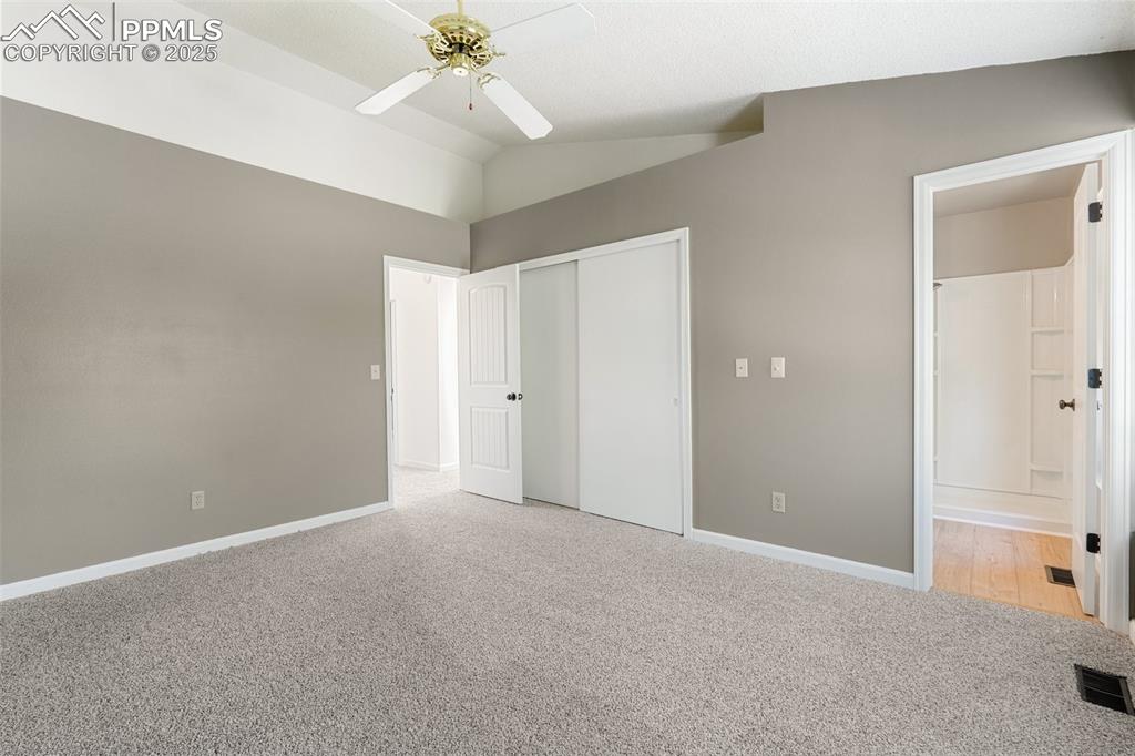 Image 16 of 22: Unfurnished bedroom with light colored carpet, lofted ceiling, a closet, co