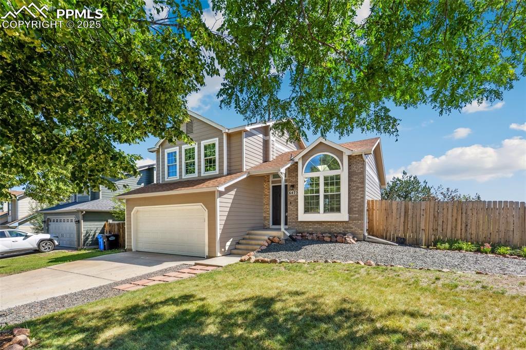 Image 2 of 22: Traditional home with an attached garage, driveway, brick siding, and a shi