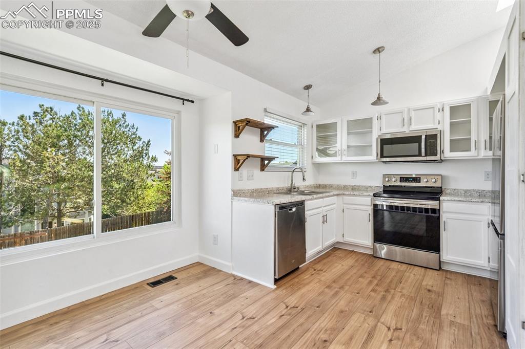 Image 6 of 22: Kitchen featuring stainless steel appliances, white cabinets, light wood-ty