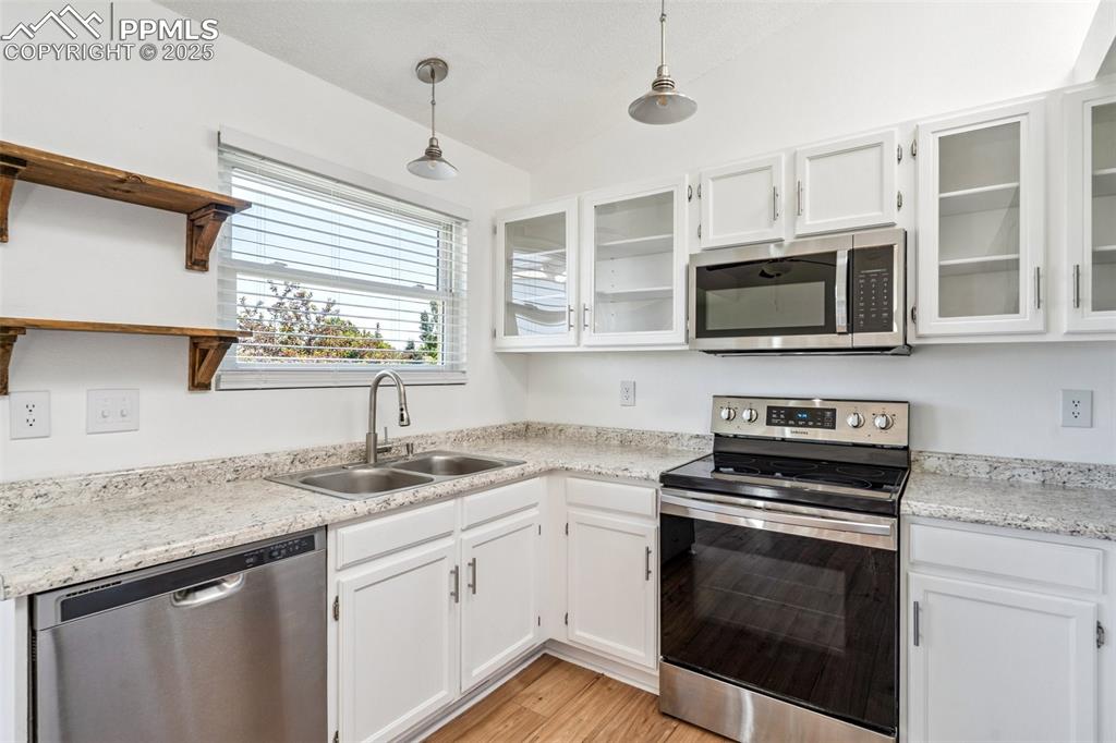 Image 8 of 22: Kitchen with appliances with stainless steel finishes, open shelves, white