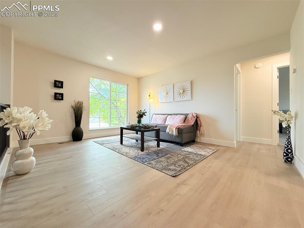 Image 11 of 50: Living area with light wood-style floors and recessed lighting
