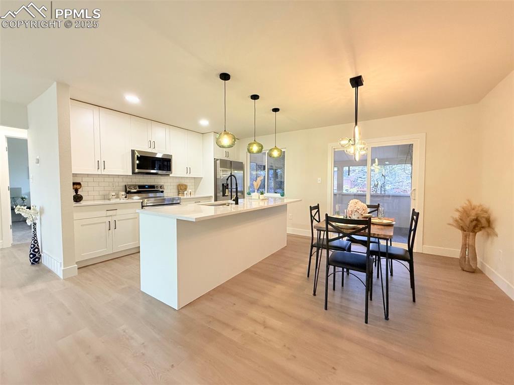Image 12 of 50: Kitchen featuring hanging light fixtures, backsplash, a chandelier, white c
