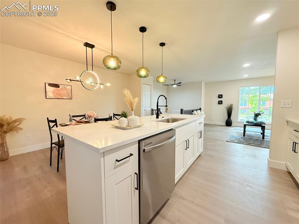 Image 14 of 50: Kitchen with white cabinets, stainless steel dishwasher, light wood-style f
