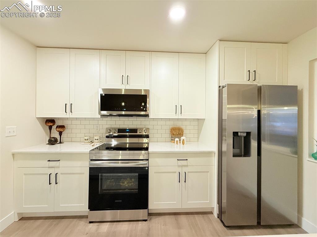 Image 15 of 50: Kitchen with stainless steel appliances, decorative backsplash, white cabin
