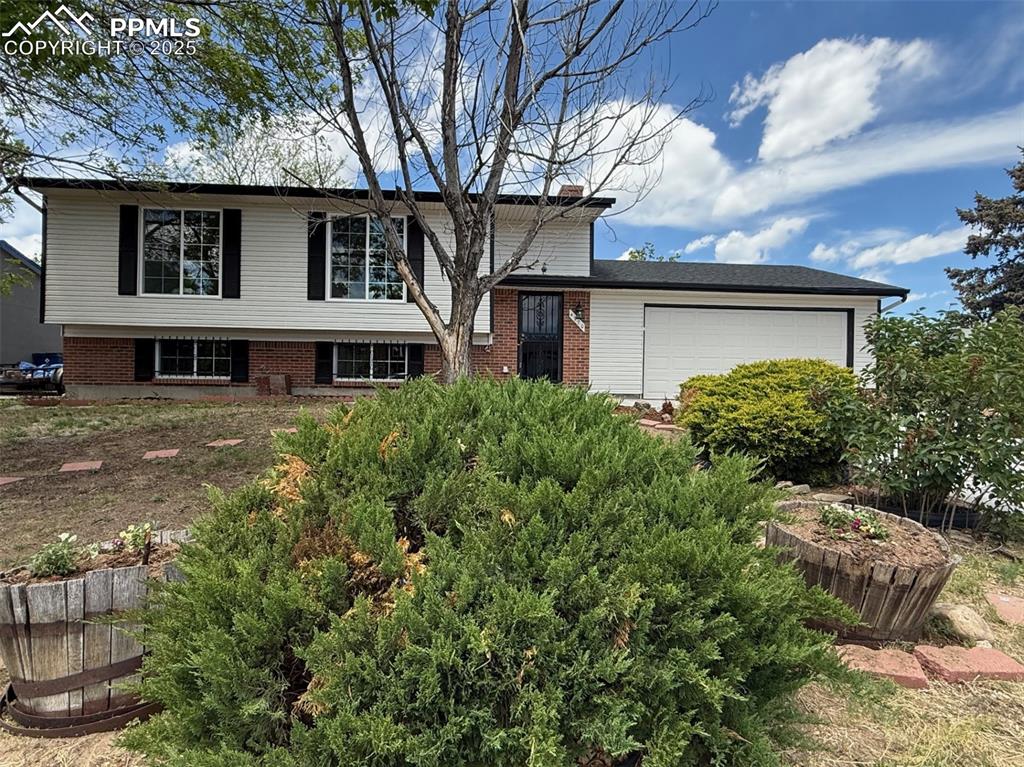 Image 2 of 50: View of front of property with brick siding, a chimney, and a garage