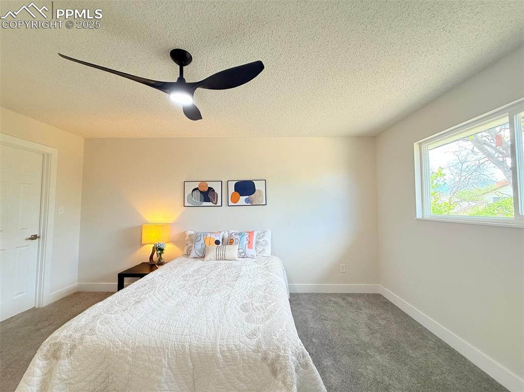 Image 22 of 50: Carpeted bedroom with a textured ceiling and ceiling fan