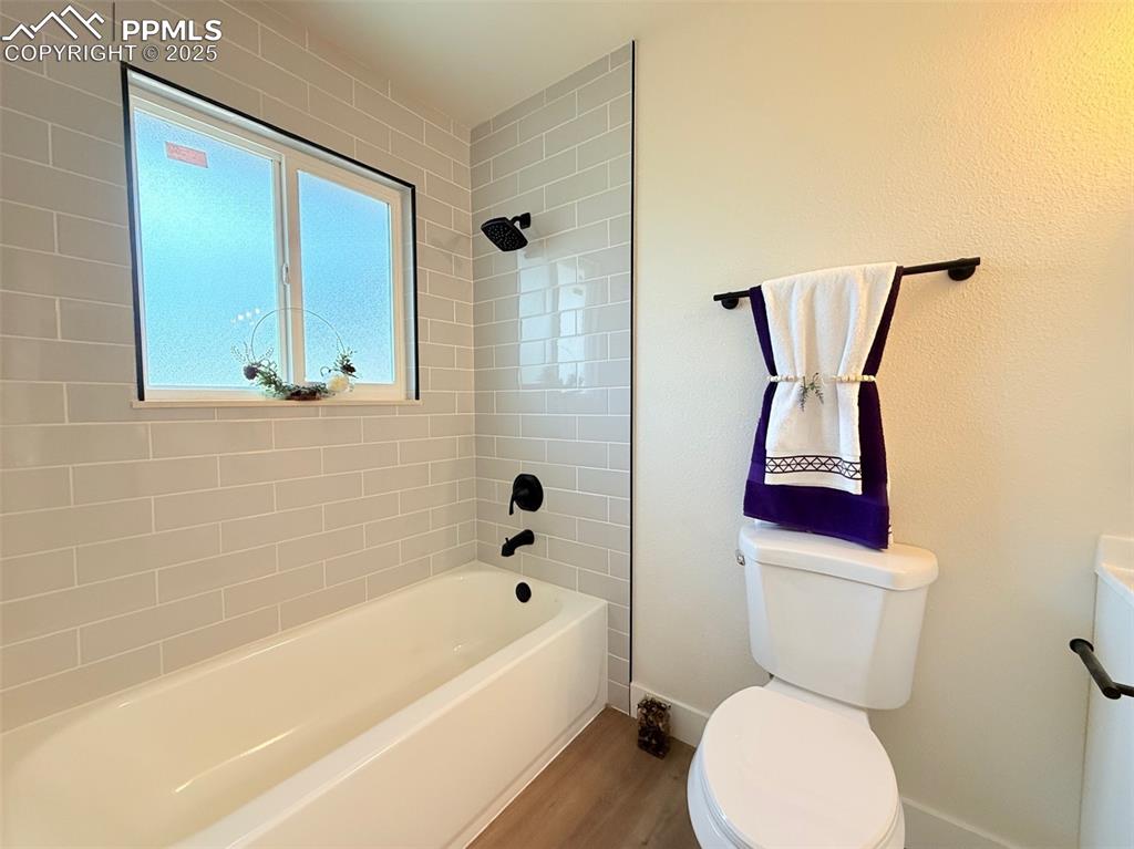 Image 24 of 50: Bathroom with tub / shower combination and wood finished floors