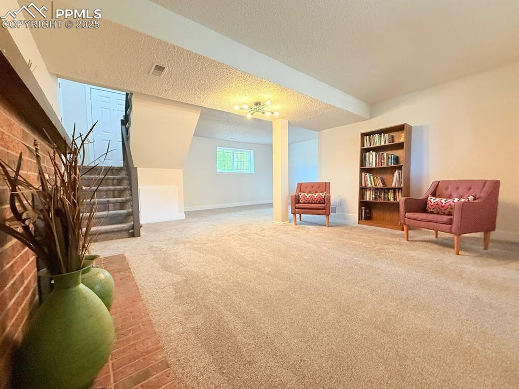 Image 36 of 50: Living area featuring light colored carpet, stairs, and a textured ceiling