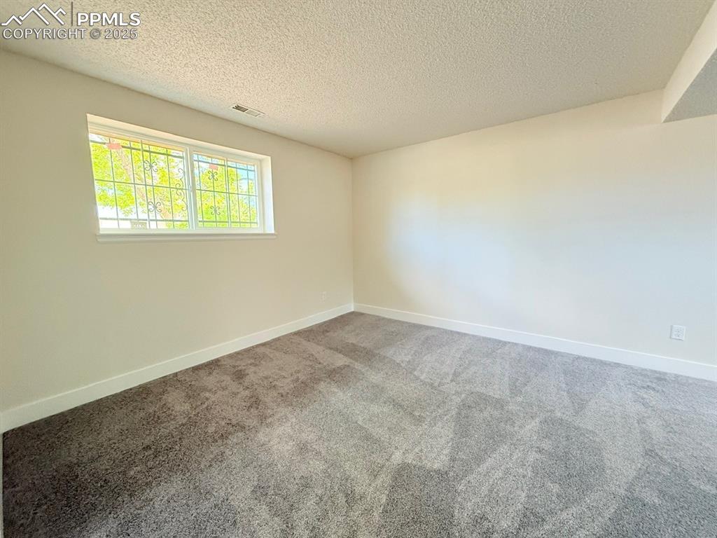 Image 40 of 50: Empty room with carpet flooring and a textured ceiling