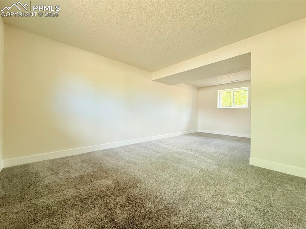 Image 41 of 50: Unfurnished room with a textured ceiling and carpet
