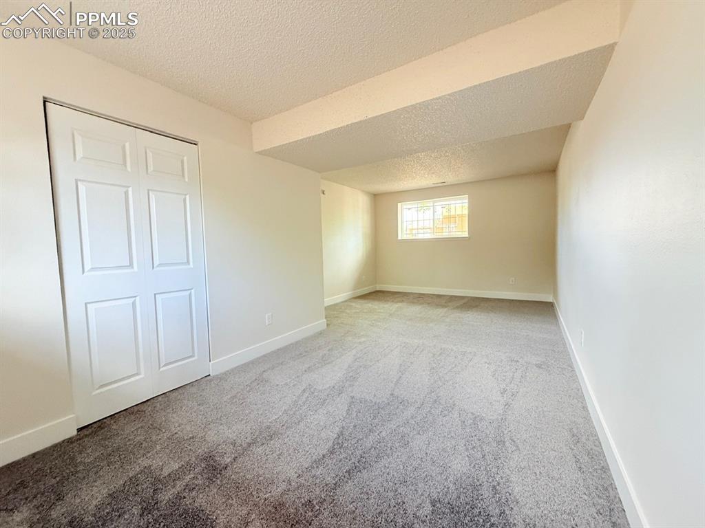 Image 42 of 50: Unfurnished bedroom with a textured ceiling, carpet, and a closet