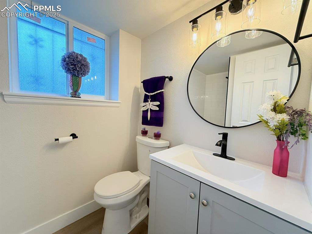 Image 43 of 50: Bathroom with vanity, a textured wall, and dark wood-style flooring