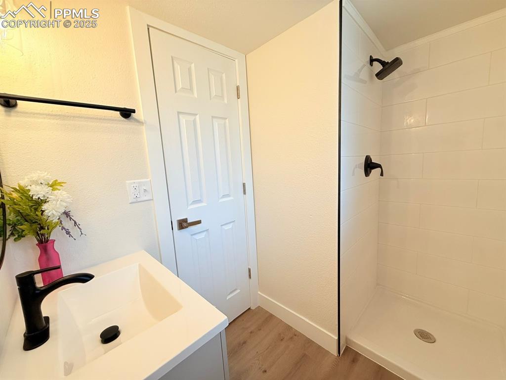 Image 44 of 50: Full bath featuring a stall shower, vanity, and light wood-style floors