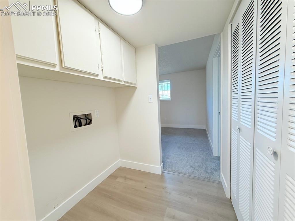 Image 46 of 50: Laundry area featuring cabinet space, light wood-style flooring, and washer