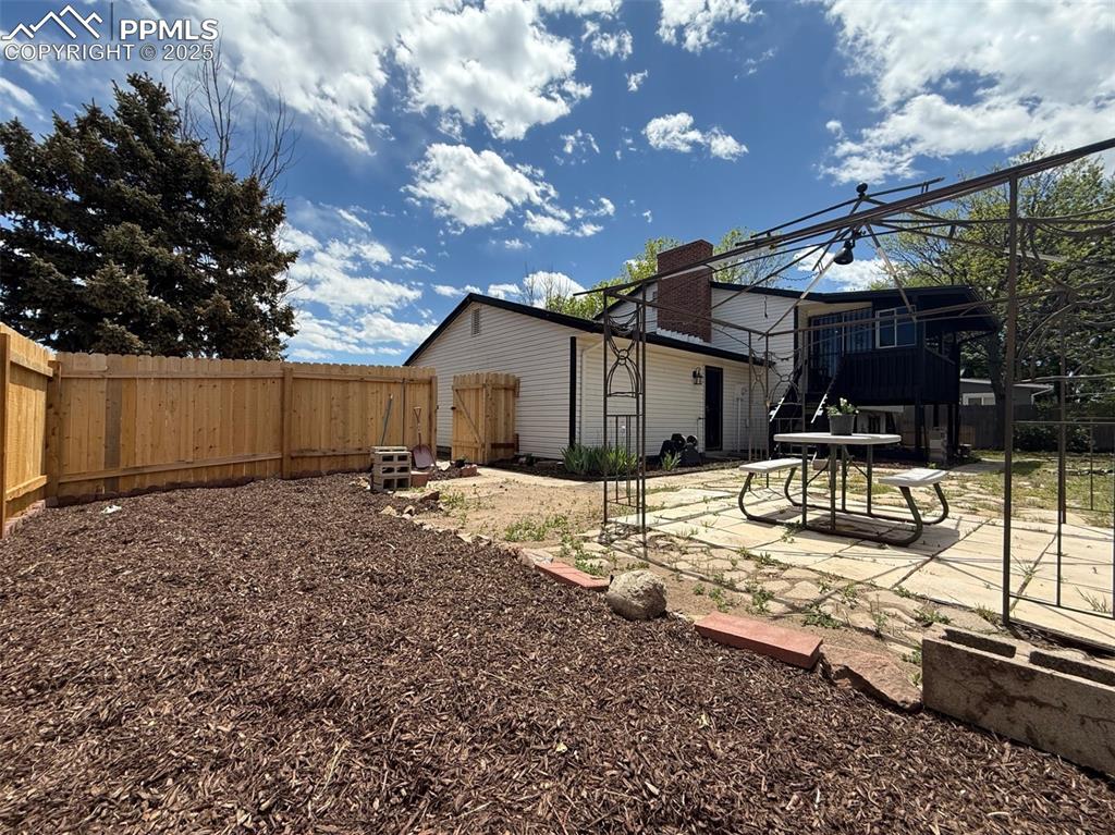 Image 47 of 50: Rear view of property with a patio, a fenced backyard, and a chimney