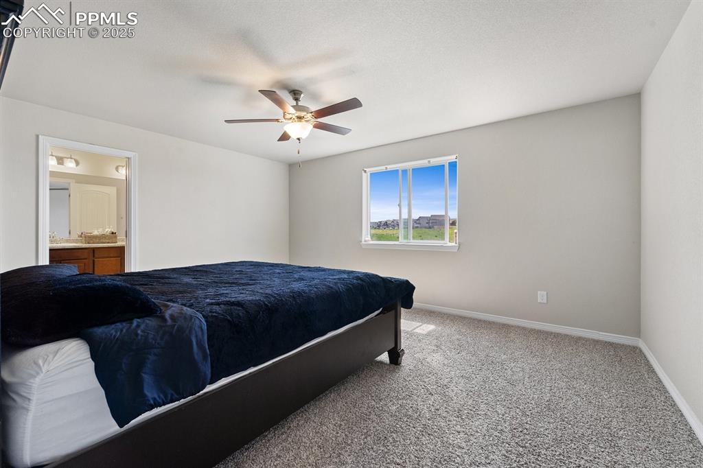 Image 16 of 22: Bedroom featuring a ceiling fan, baseboards, carpet flooring, and ensuite b