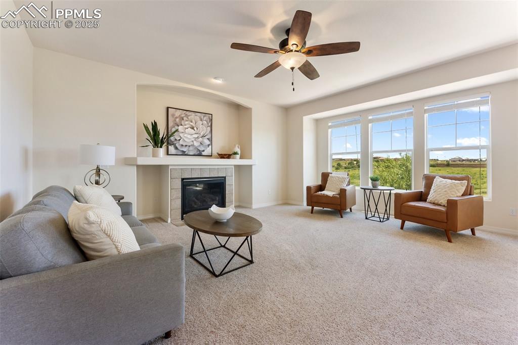Image 12 of 48: Carpeted living room with a tile fireplace and a ceiling fan