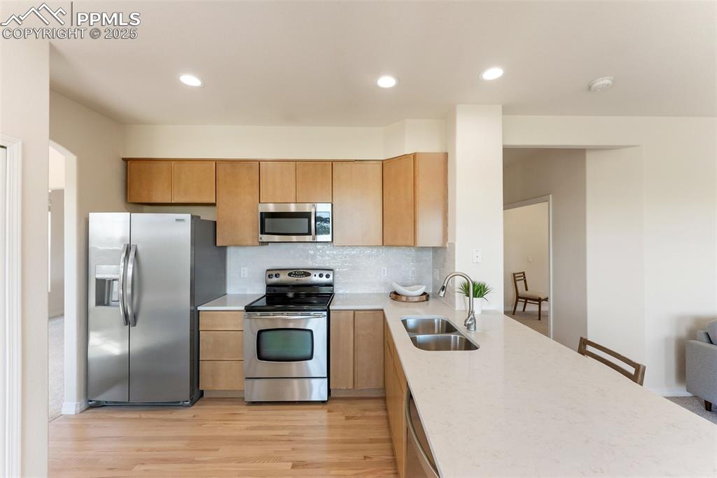 Image 17 of 48: Kitchen featuring stainless steel appliances, light wood-type flooring, tas
