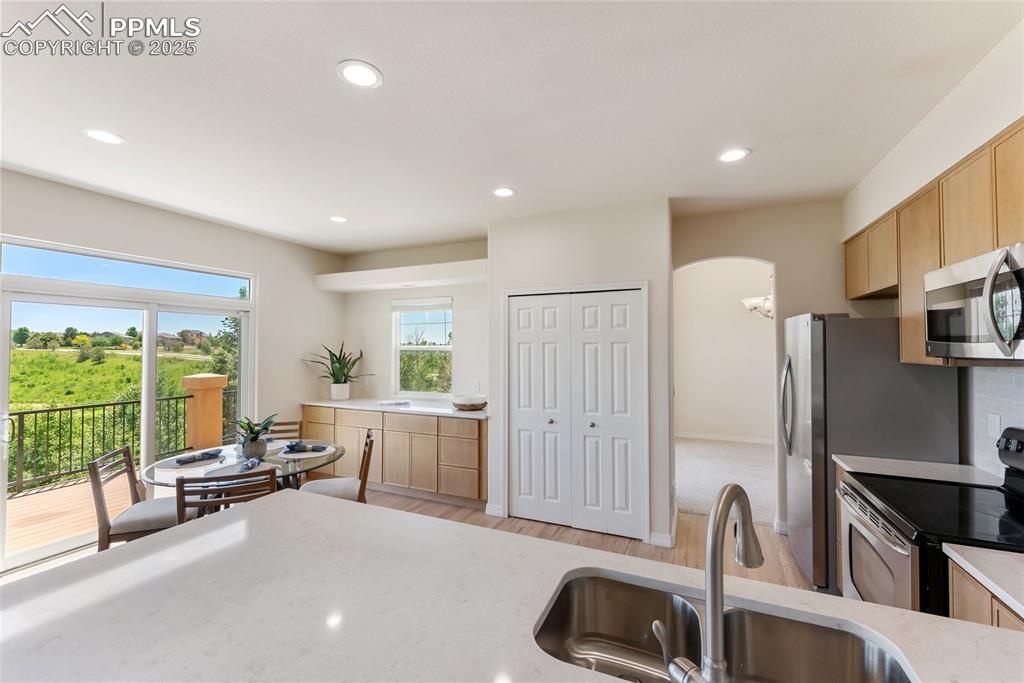 Image 21 of 48: Kitchen with stainless steel appliances, light stone countertops, light bro