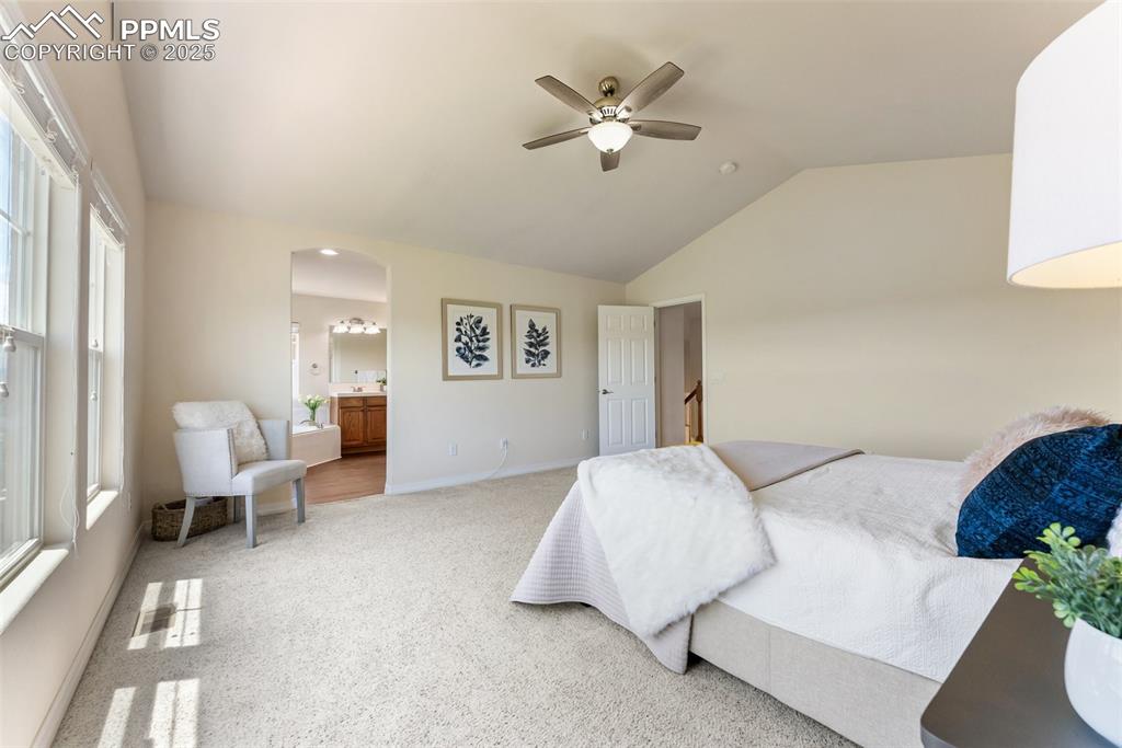 Image 27 of 48: Bedroom with arched walkways, carpet floors, vaulted ceiling, ensuite bathr