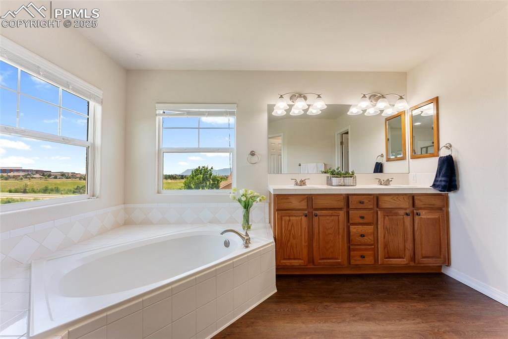 Image 29 of 48: Full bath featuring double vanity, a garden tub, and wood finished floors