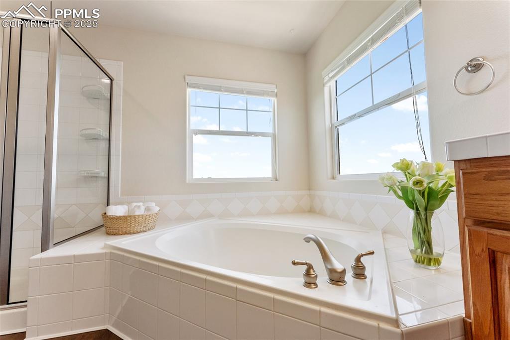 Image 30 of 48: Bathroom featuring a garden tub and a shower stall