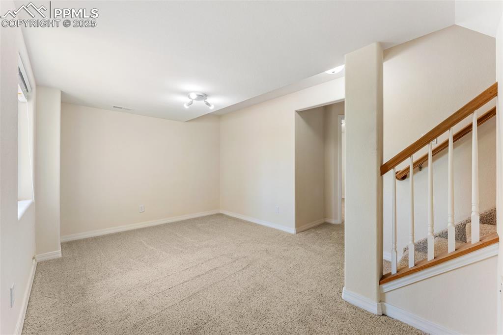 Image 32 of 48: Carpeted empty room featuring baseboards and stairs