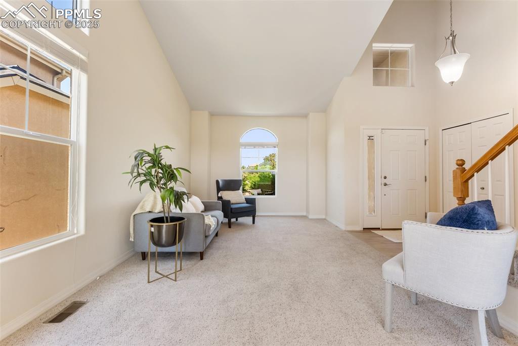 Image 6 of 48: Carpeted entryway featuring high vaulted ceiling and stairs