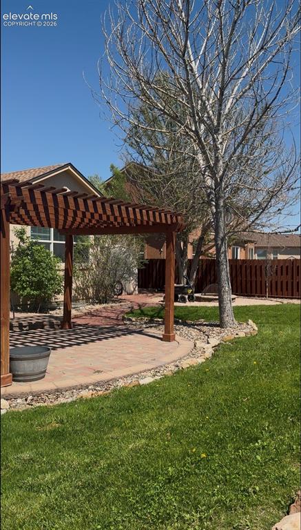 Image 34 of 34: Backyard featuring a wooden pergola over a paver patio with a stone border