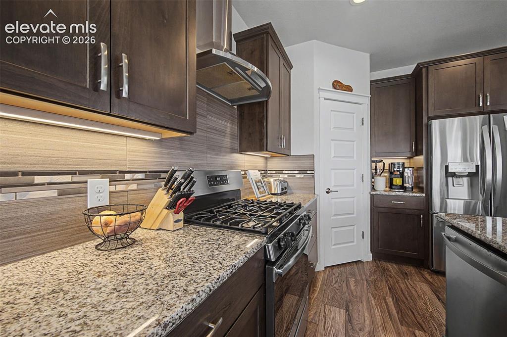 Image 11 of 45: The kitchen features a gas range and decorative hood.